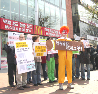 몸에 나쁜 햄버거를 전 세계 어린이에게 내다 파는 패스트푸드 가게는 그만 사라져야 한다고 생각하는 어른들이에요. 이 사진은 '환경정의'라는 단체에서 찍었습니다.